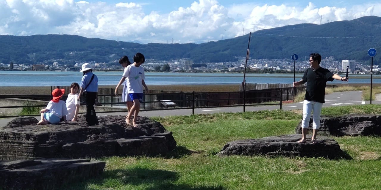 水辺の高台を歩く子どもたち