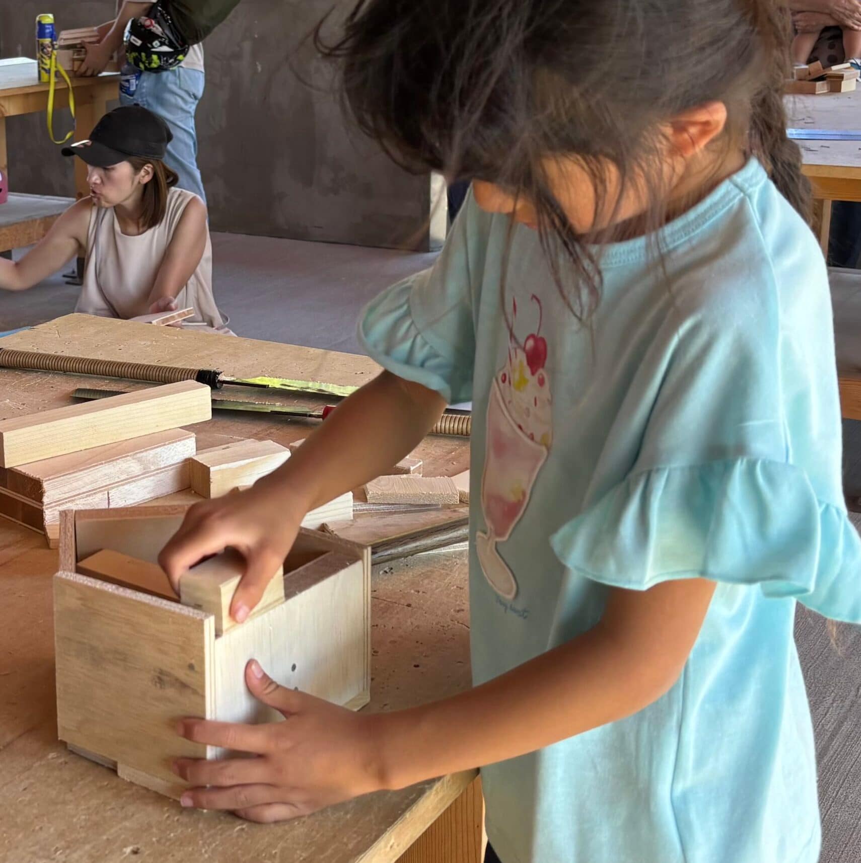 木箱に手を入れて作業する子どもの手元