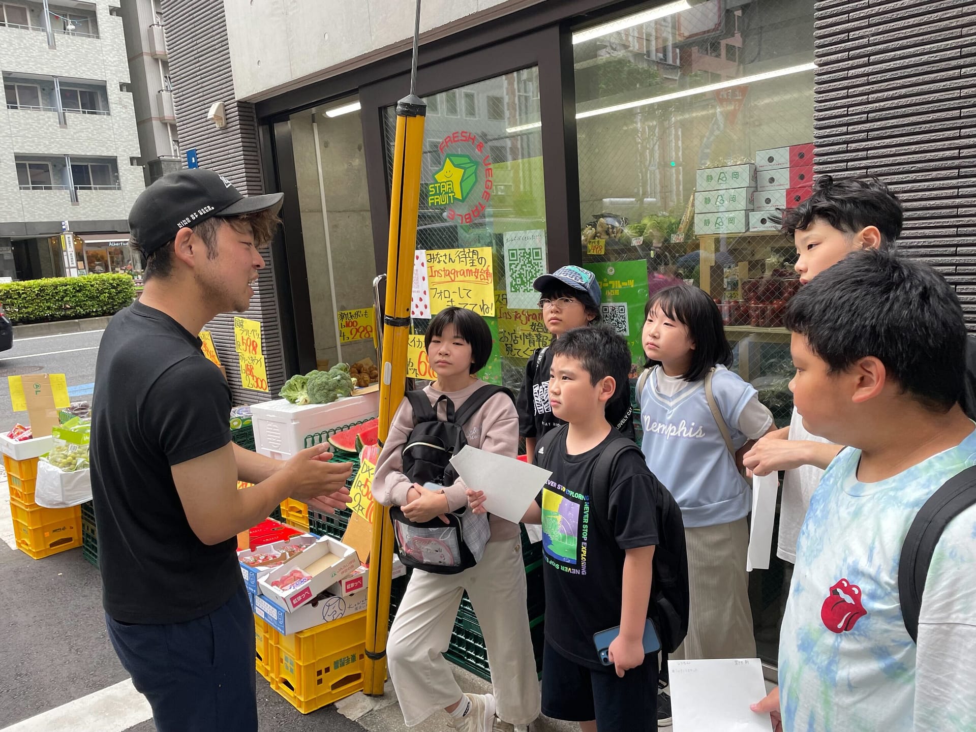 屋外で大人と子どもたちが集まって荷物を受け渡している