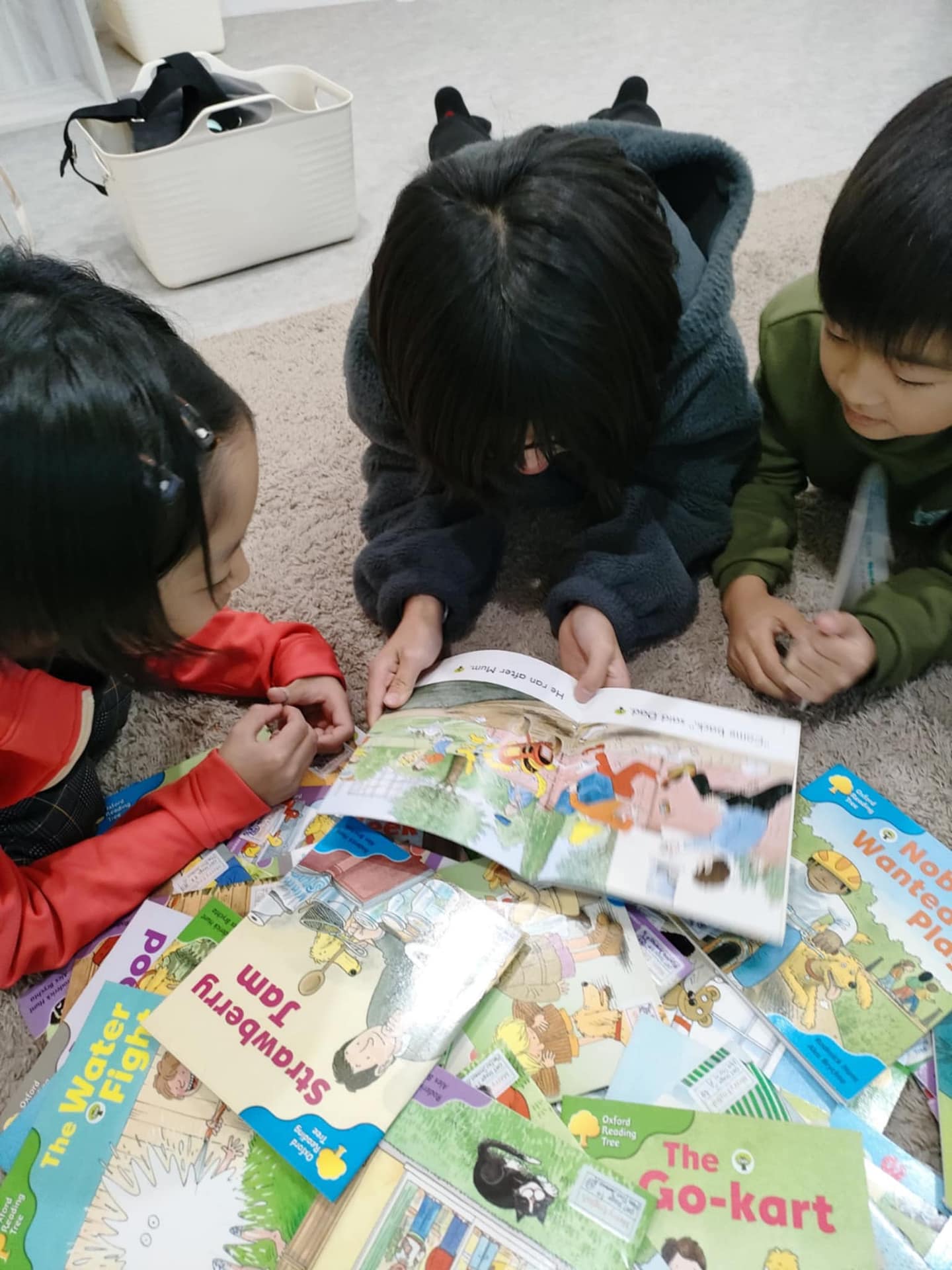 床に絵本を広げて一緒に読む子どもたち