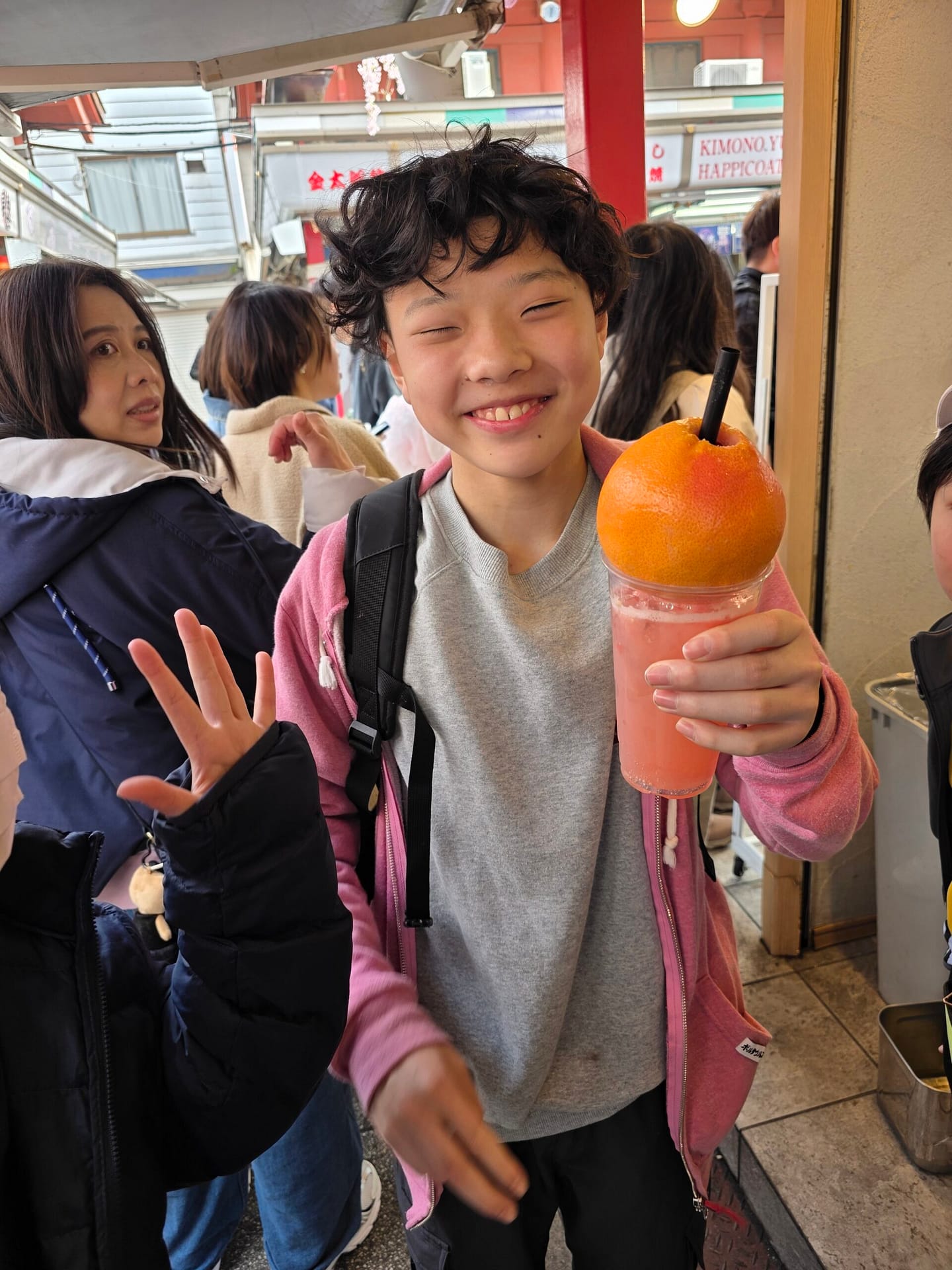 屋外のイベントで飲み物を手に笑う子ども