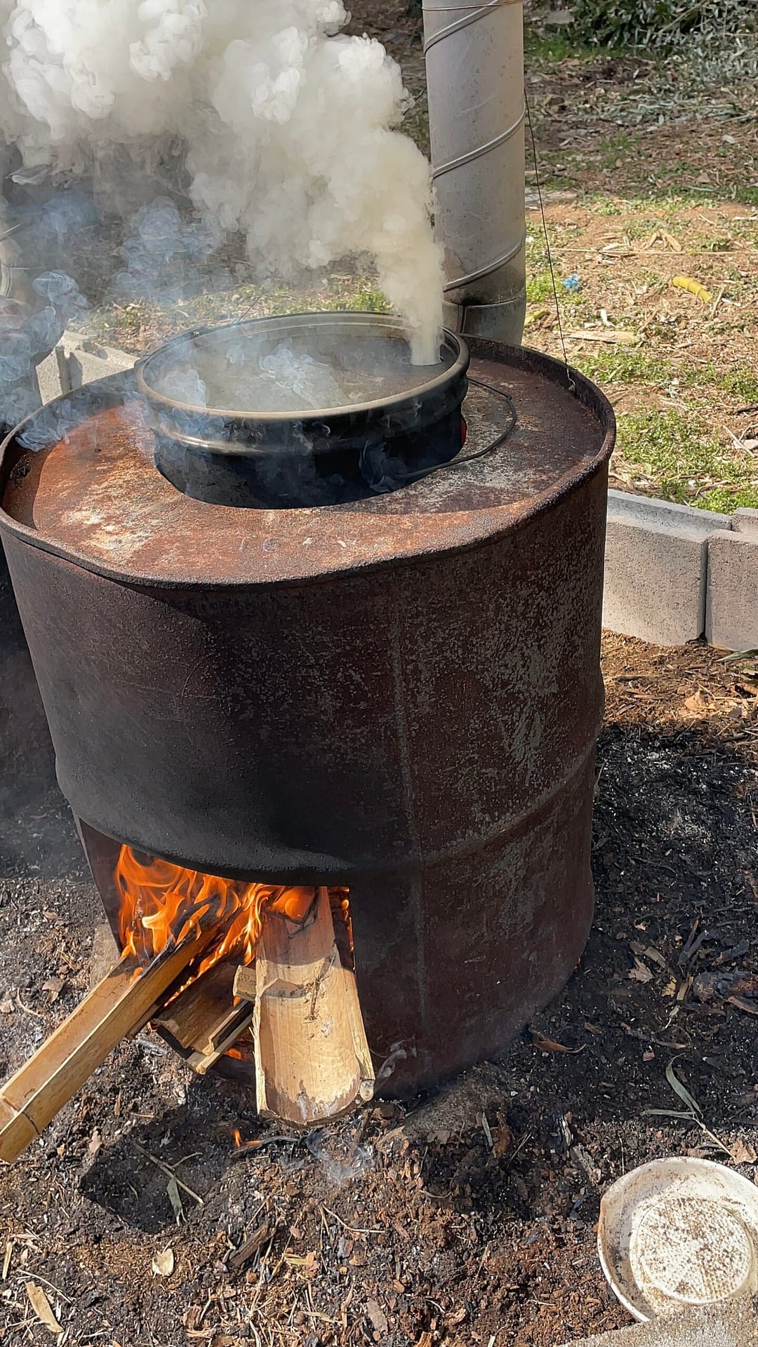 屋外のかまどに火を入れる様子